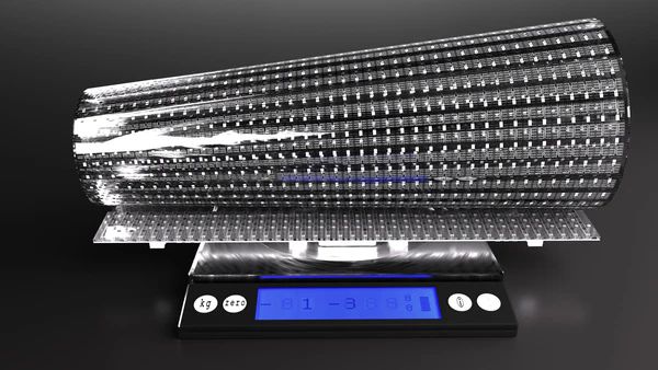 A rolled transparent LED film panel resting on a digital kitchen scale