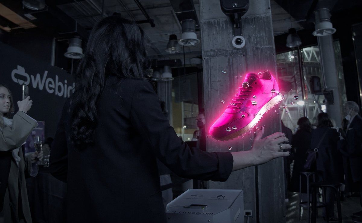 Visitor interacting with a floating hologram display in a dark room